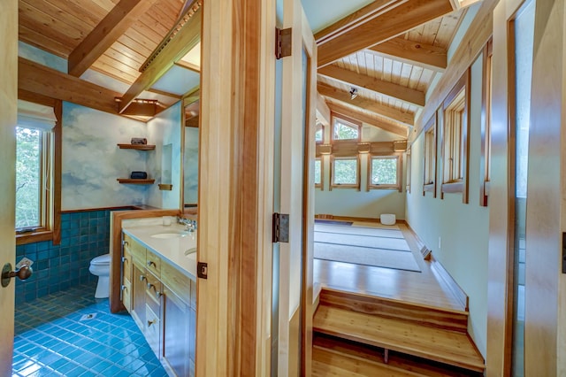 bathroom featuring tile walls, lofted ceiling with beams, vanity, wooden ceiling, and toilet