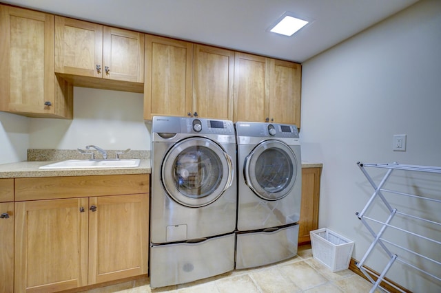 laundry area with cabinets, washing machine and clothes dryer, and sink