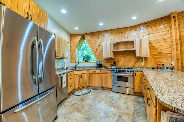 kitchen with light stone countertops, wooden walls, stainless steel appliances, and sink