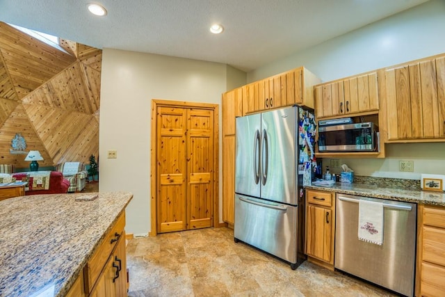 kitchen with appliances with stainless steel finishes, a textured ceiling, and light stone counters