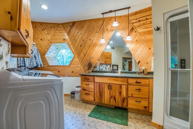 bathroom with wood walls, washer and dryer, and vanity