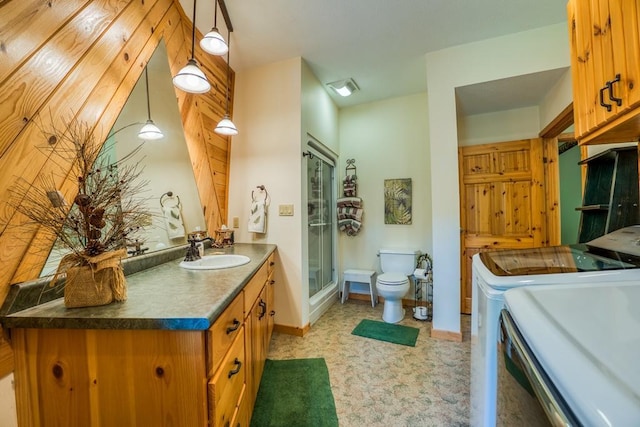 bathroom with vanity, toilet, washing machine and clothes dryer, and an enclosed shower