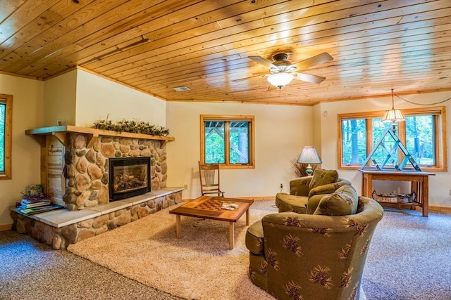 carpeted living room featuring wood ceiling, ceiling fan, and a stone fireplace