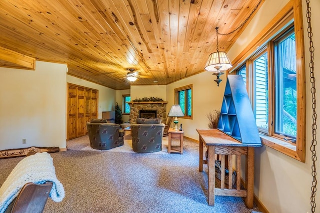 living room with ceiling fan, a stone fireplace, and wood ceiling