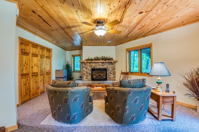 carpeted living room featuring wood ceiling, ceiling fan, and a stone fireplace