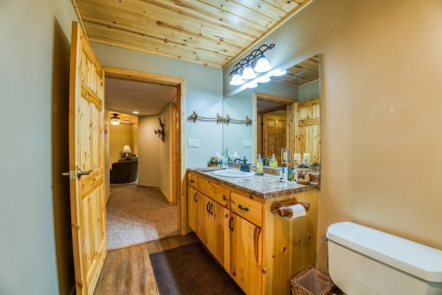 bathroom with hardwood / wood-style floors, wood ceiling, vanity, and toilet