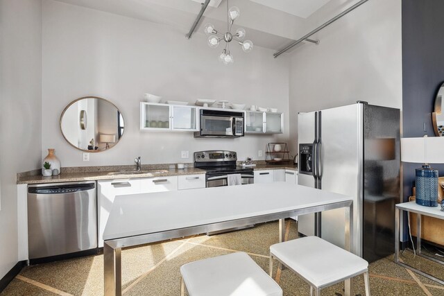 kitchen featuring white cabinets, sink, appliances with stainless steel finishes, an inviting chandelier, and a kitchen bar