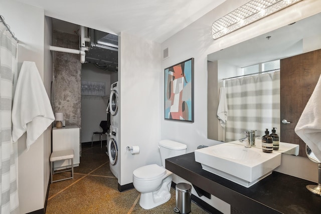 bathroom featuring stacked washer and dryer, vanity, and toilet