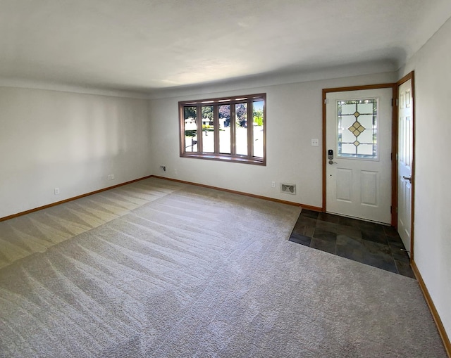 foyer entrance featuring dark colored carpet