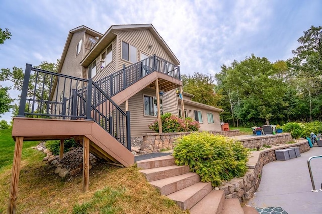 rear view of property with a wooden deck and a patio