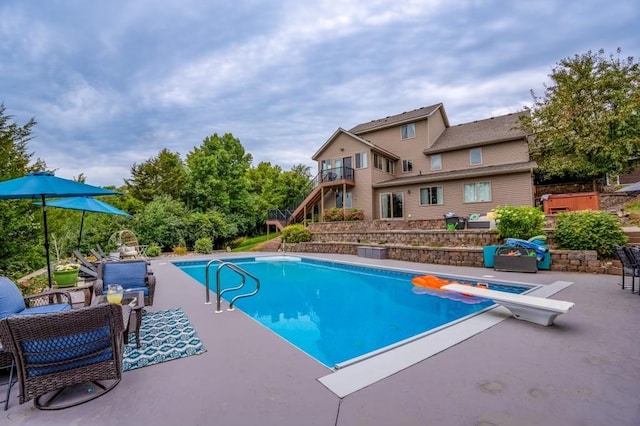 view of pool with a diving board and a patio area