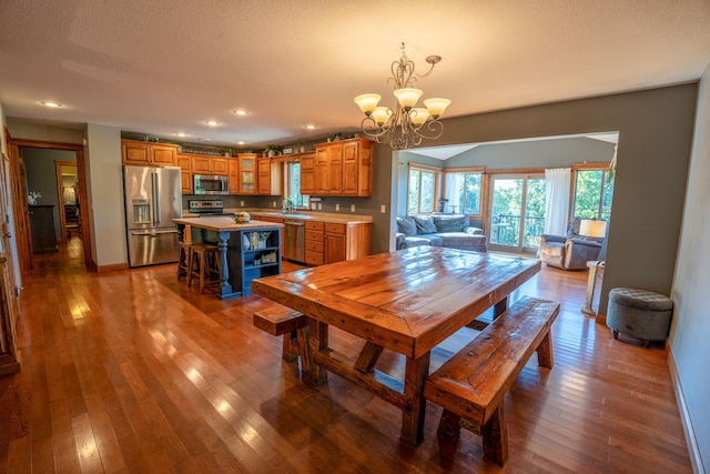 dining room with an inviting chandelier, sink, dark wood-type flooring, and a textured ceiling