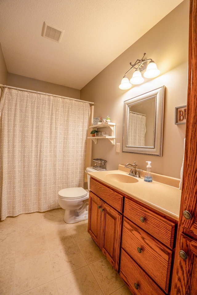 bathroom with tile patterned flooring, a textured ceiling, vanity, and toilet