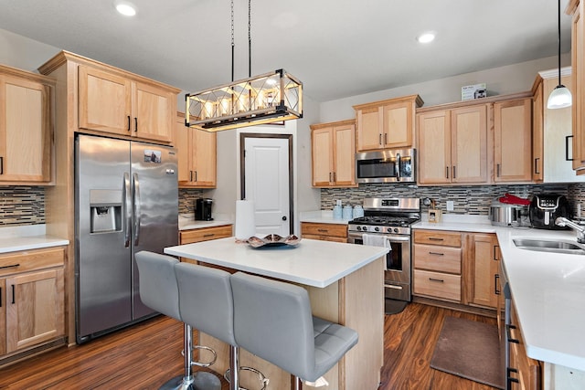 kitchen featuring a kitchen bar, sink, decorative light fixtures, dark hardwood / wood-style flooring, and stainless steel appliances