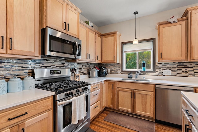 kitchen with pendant lighting, appliances with stainless steel finishes, sink, backsplash, and dark wood-type flooring