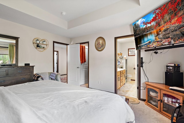 carpeted bedroom with ensuite bathroom and a raised ceiling