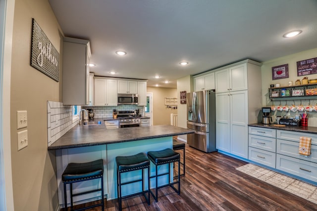 kitchen featuring dark wood-type flooring, tasteful backsplash, a breakfast bar area, stainless steel appliances, and sink