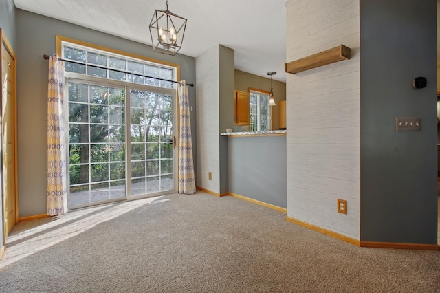 interior space with carpet floors, an inviting chandelier, and a textured ceiling