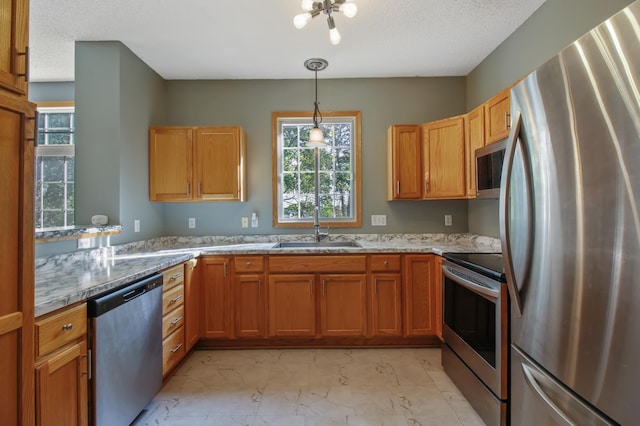 kitchen with light stone countertops, sink, appliances with stainless steel finishes, decorative light fixtures, and a textured ceiling