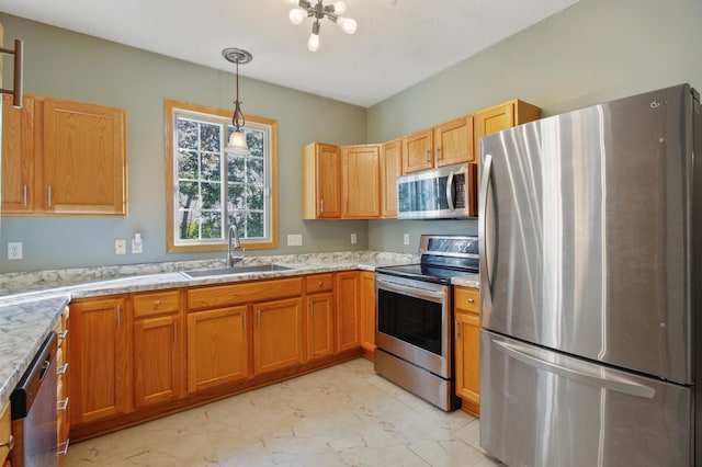 kitchen featuring sink, a textured ceiling, decorative light fixtures, appliances with stainless steel finishes, and light stone countertops