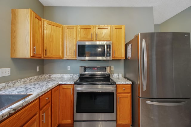 kitchen with sink, stainless steel appliances, and a textured ceiling