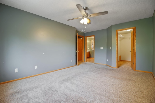 unfurnished bedroom with ceiling fan, a textured ceiling, a closet, a spacious closet, and light colored carpet