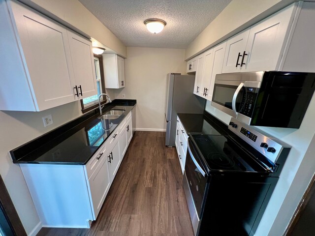 kitchen featuring dark wood-type flooring, white cabinets, stainless steel appliances, a textured ceiling, and sink