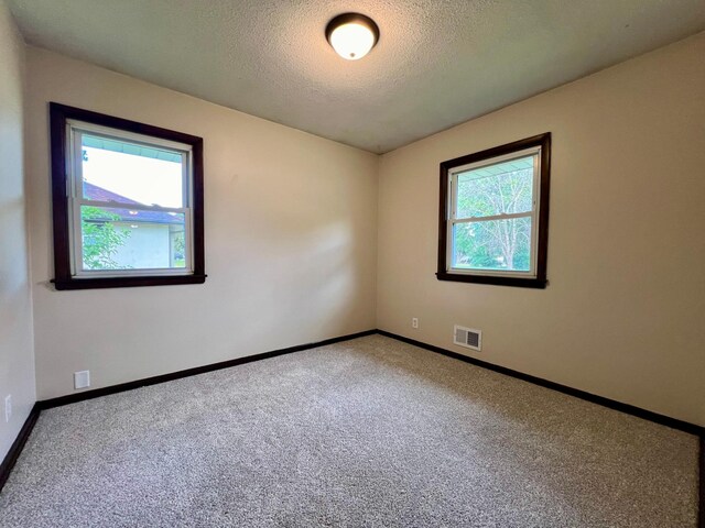 unfurnished room featuring a textured ceiling and carpet