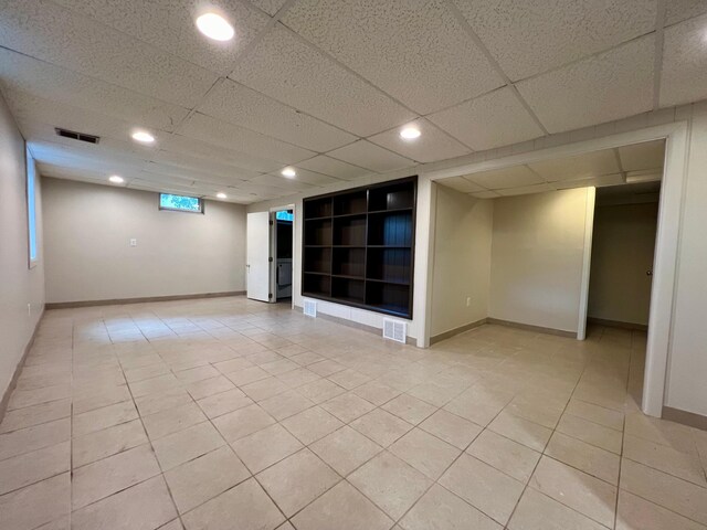 interior space featuring built in features, light tile patterned floors, and a paneled ceiling