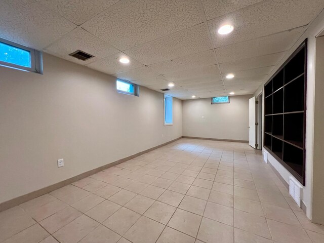 interior space with a drop ceiling and light tile patterned flooring