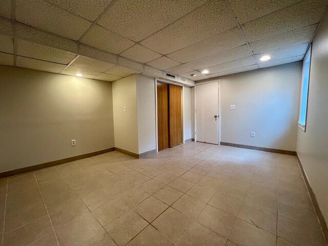 unfurnished room with a paneled ceiling and light tile patterned floors