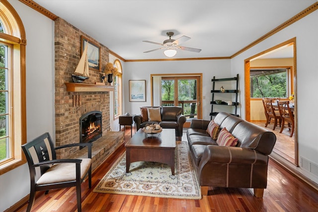 living room with a fireplace, ornamental molding, hardwood / wood-style floors, and ceiling fan