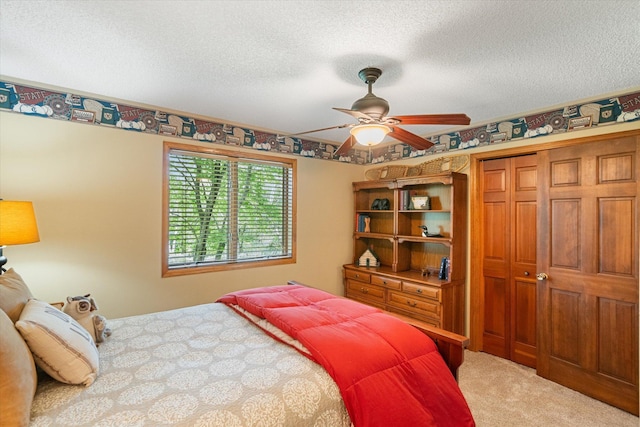 bedroom with ceiling fan, a textured ceiling, a closet, and carpet floors