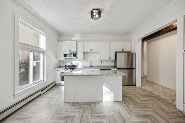 kitchen featuring light parquet flooring, baseboard heating, white cabinetry, stainless steel appliances, and light stone countertops