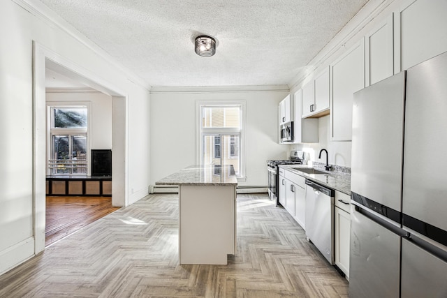 kitchen featuring sink, white cabinetry, appliances with stainless steel finishes, light parquet floors, and light stone countertops