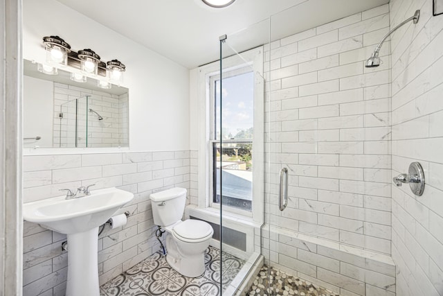 bathroom featuring tile walls, toilet, an enclosed shower, and a healthy amount of sunlight