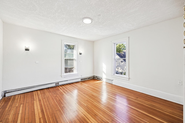 empty room featuring a baseboard heating unit, a textured ceiling, and hardwood / wood-style floors