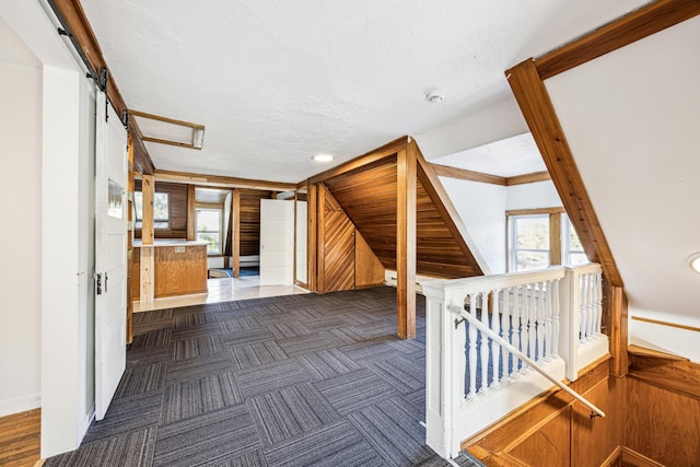 interior space with wood walls, a textured ceiling, and a barn door