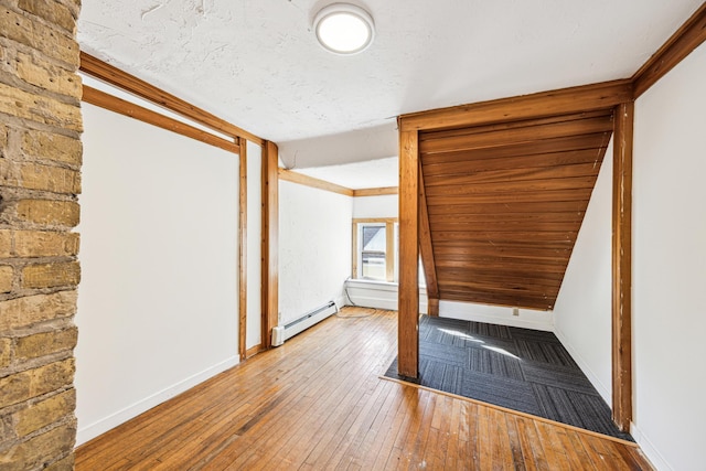 spare room featuring a textured ceiling, crown molding, hardwood / wood-style floors, and a baseboard heating unit