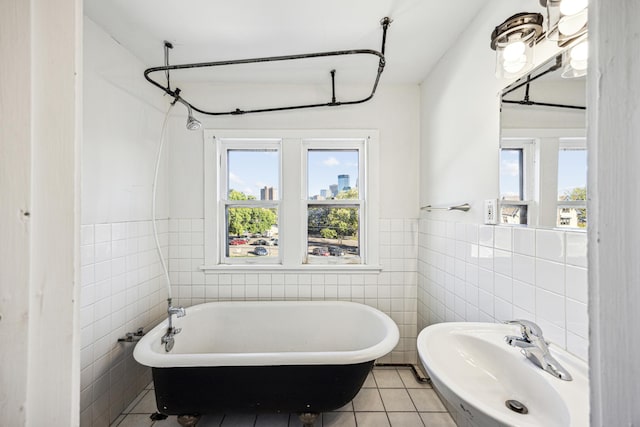 bathroom featuring tile walls, tile patterned flooring, a washtub, and sink