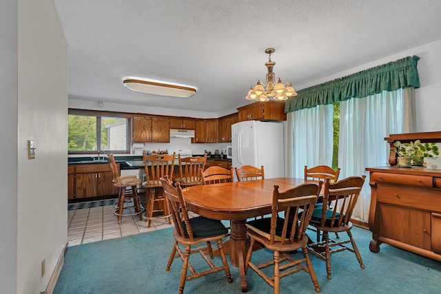 tiled dining area featuring a textured ceiling, an inviting chandelier, and sink