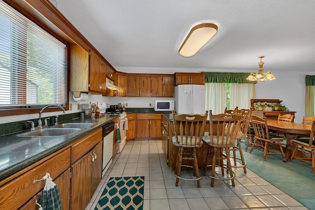 kitchen featuring white appliances, a healthy amount of sunlight, a chandelier, and a sink