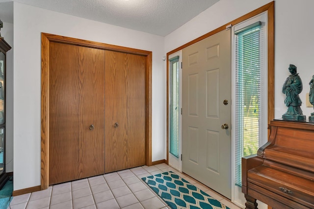 foyer with light tile patterned floors, baseboards, and a textured ceiling