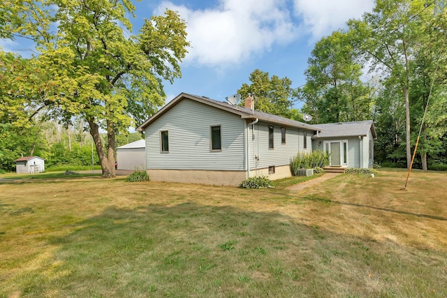 view of side of property with a chimney, an outdoor structure, a storage shed, and a lawn