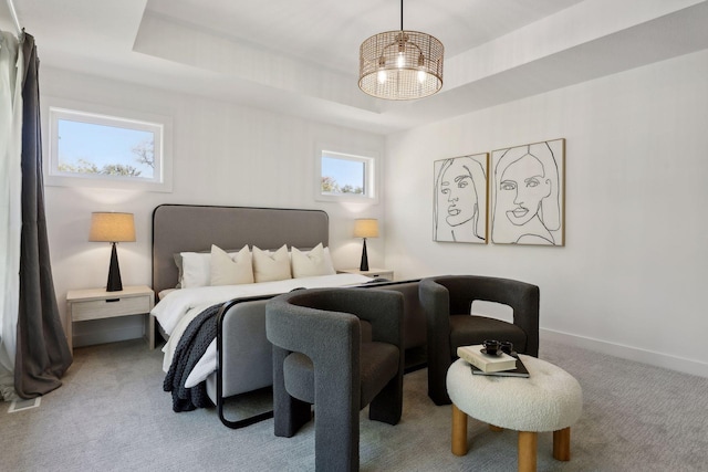 carpeted bedroom with a tray ceiling and multiple windows