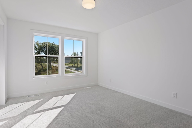 spare room with baseboards, visible vents, and light colored carpet