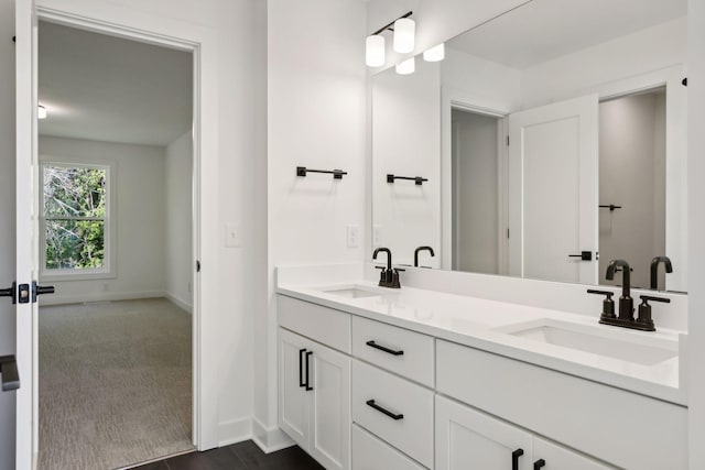 bathroom with double vanity, baseboards, and a sink