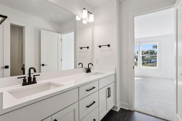 full bath with double vanity, baseboards, and a sink