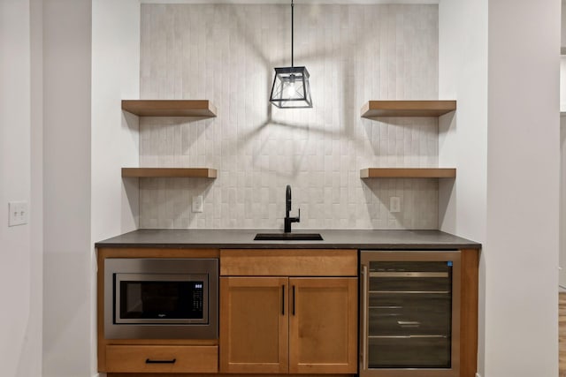 bar with indoor wet bar, stainless steel microwave, decorative backsplash, a sink, and beverage cooler