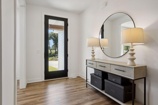 foyer entrance with baseboards, a wealth of natural light, and light wood-style floors